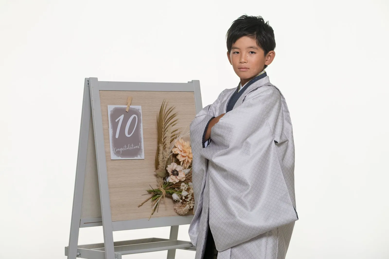 「10」のボードの横で腕を組む羽織袴の男の子