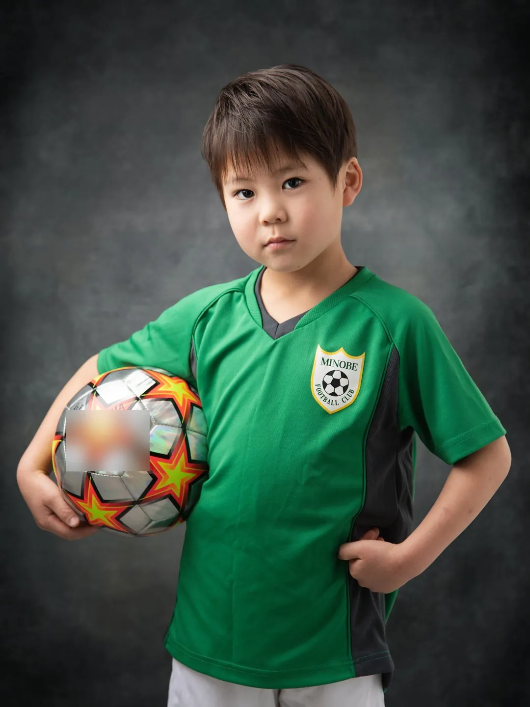サッカーのユニフォームでボールを抱える男の子