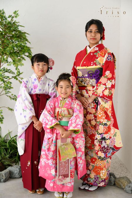 豪華な和装をまとった3人の女性が並び微笑む姿。姉妹が鮮やかな着物で記念撮影。