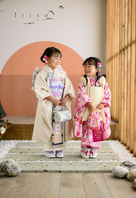 優雅な和服を着た2人の女の子が、笑顔で向き合いながら撮影スタジオでポーズを取る。