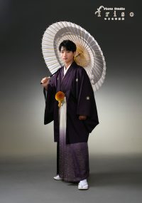 紫色の袴姿の男性が和傘を手に持ち、フォーマルなポーズで撮影されたスタジオ写真。