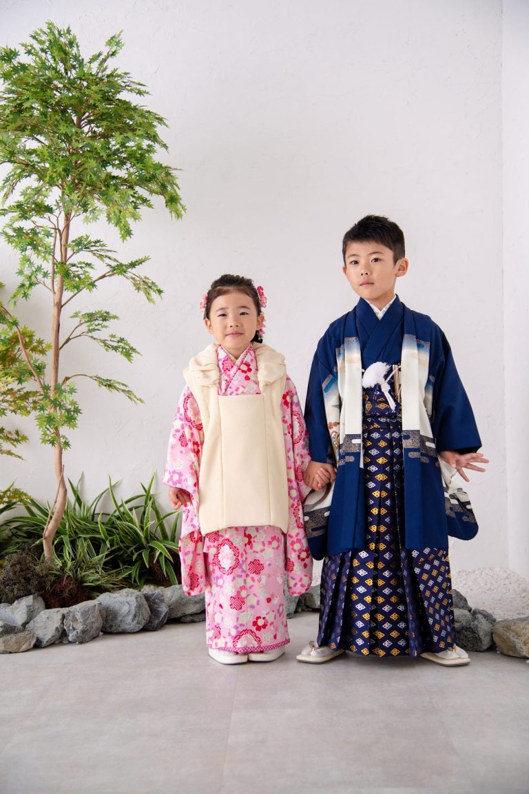 七五三衣装を着た男の子と女の子が手をつないで立っている写真。ピンクの着物に身を包んだ女の子と、凛々しい羽織袴姿の男の子。