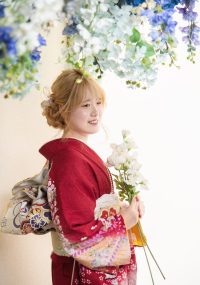花のカーテンの下でほほ笑む振袖のお嬢様