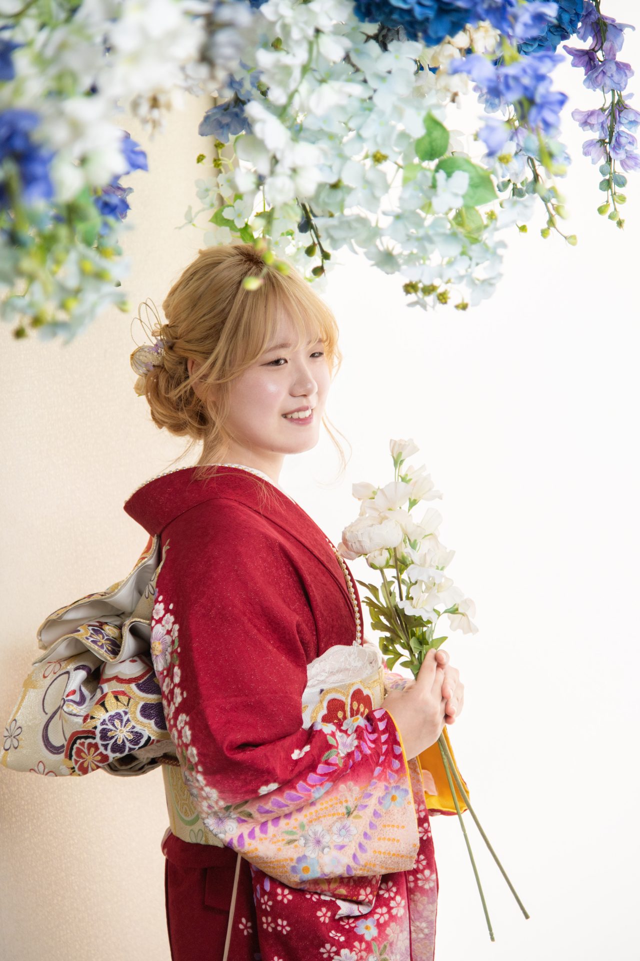 花のカーテンの下でほほ笑む振袖のお嬢様