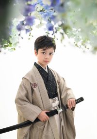 花のカーテンの下、日本刀を手にキリっとした表情の男の子