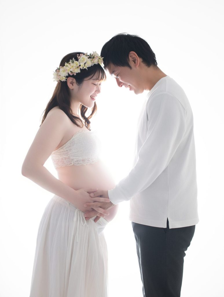 明るい照明の中お腹の赤ちゃんを優しくなでるご夫婦