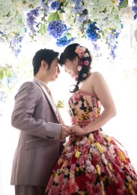 花のカーテンの下、おでこを寄せしずかにほほ笑む夫婦
