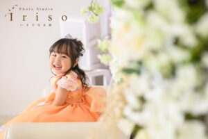 オレンジのドレスで笑う3歳の女の子と白い花